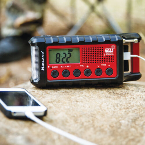 
                  
                    Midland ER310 emergency hand crank radio with flashlight charging a phone outdoors.
                  
                