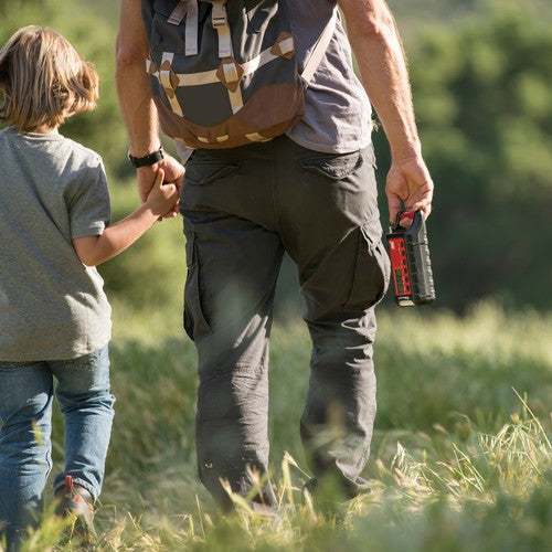
                  
                    Parent holding a Midland ER310 Emergency Hand Crank Radio while walking with a child in a grassy field.
                  
                